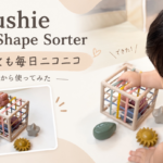 mushie Elastic Shape Sorterの商品と、子どもが遊んでいる様子。取れなくても毎日ニコニコ、10か月から使ってみた。